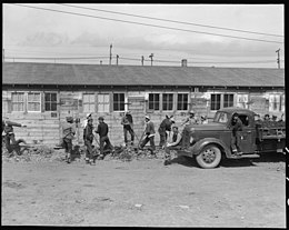 All maintenance work, repair and construction is done by volunteer workers of Japanese ancestry. This gang of boys and young men are digging a drainage tank along the front of one of the barracks. Lange, 1942. San Bruno, California. All maintenance work, repair and construction is done by volunteer workers o . . . - NARA - 537926.jpg