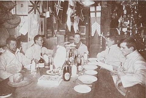 Five men seated for a meal with flags and festive decorations