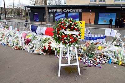 Memorial to the people killed in the January 2015 Ile-de-France attacks The Wreath Laid by Secretary Kerry and French Foreign Minister Fabius Is Pictured Outside the Hyper Cacher Kosher Market in Paris (16106400057).jpg