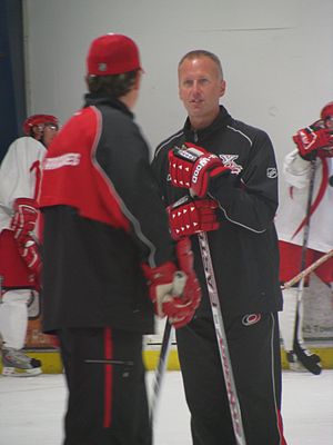 Photo de Tom Barrasso en survêtement sur la patinoire qui discute avec une personne de dos.