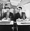 Two men on Northwest Airlines aircraft, one using typewriter, with female flight attendant in background (4670206226).jpg