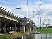 Steel poles and lattice towers of Hermosa-Duhat-Balintawak 230,000 volt transmission line along Candaba Viaduct of North Luzon Expressway (NLEx) in Apalit, Pampanga. The Hermosa-San Jose 500,000 volt transmission line, which intersects with the said 230,000 volt line on Calumpit, Bulacan portion of the viaduct, can be seen along the viaduct. Views of Candaba Viaduct Apalit Bypass Road fields 24.jpg