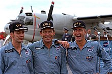 Fotografía en color de los tres miembros de la tripulación del Apollo 7, con una gorra de Essex después de su misión.