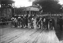 Coureurs cyclistes alignés au départ d'une épreuve sur piste.