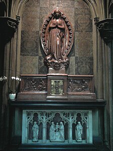 The red marble statue of the Virgin of Lourdes on the lateral altar of the transept