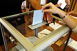 A voter putting her envelope into a clear ballot box during the 2007 French presidential election.