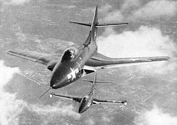 A swept-wing F9F-6 Cougar (foreground) and a straight-wing F9F-5 Panther in flight