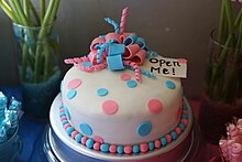 An uncut gender reveal cake decorated with pink and blue on a white base, using both pink and blue to represent ambiguity before the reveal Gender-reveal-cake.jpg