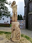 Dřevěná socha „Šumava“ od Jiřího Nekoly před kostelem (srpen 2020)