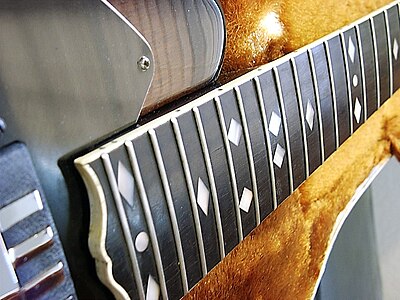 An example of the ivory binding and mother of pearl fret marker inlays Ovation Deacon Fretboard Inlay and Binding.JPG