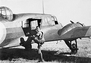 Vue de trois quarts arrière d'un avion militaire bimoteur, embarqué par un homme en tenue de vol