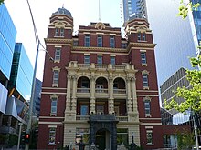 Main pavilion of the former Queen Vic Hospital, which is now the Queen Victoria Women's Centre, wedged between the glass corporate boxes of the Sensis and BHP headquarters; it is listed on the Victorian Heritage Register (H0956). Queen victoria hospital main pavillion melbourne.jpg