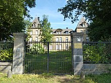 Photographie récente du chateau, depuis la grille, avec une plaque de l'OPAC