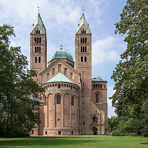 Looking toward the choir of a brick Romanesque cathedral. The twin bell towers, the transept crossing dome, and the roof are green copper.