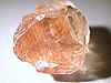 A multi-surfaced, pink rock with light reflecting at various points.