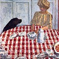 Tableau dont le premier plan est une table ronde couverte d'une nappe à carreaux et de quelques objets, avec derrière une femme assise et un chien noir, sur fond de boiserie blanche