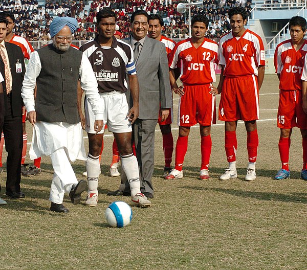 Then Prime Minister of India, Manmohan Singh, with JCT players (in red) during the inauguration of 2006–07 National Football League.