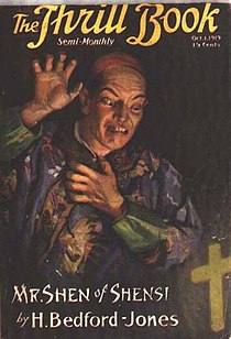 A man in Chinese dress raising a hand threateningly, against a dark background