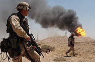 US_Navy_030402-N-5362A-004_U.S._Army_Sgt._Mark_Phiffer_stands_guard_duty_near_a_burning_oil_well_in_the_Rumaylah_Oil_Fields_in_Southern_Iraq.jpg