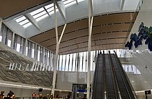 Intérieur spacieux de la gare avec des murs blancs et un plafond beige et de grandes fenêtres en hauteur sur les murs