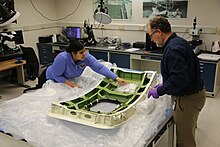 NTSB staff examine the door plug in the NTSB materials laboratory Alaska Airlines door plug inspected at NTSB lab.jpg