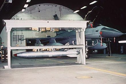 Weapons Storage and Security System vault in raised position holding a B61 nuclear bomb, adjacent to an F-16. The vault is within a Protective Aircraft Shelter.