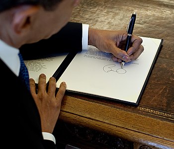English: President Barack Obama writes at his ...