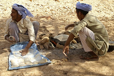 Two young Bedouins making bread in the desert