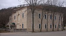 Rushford Wagon and Carriage Company, now an apartment building, with "Rushford" on the side of the bluff behind it. CarriageHouseAptsRushfordMN.jpg