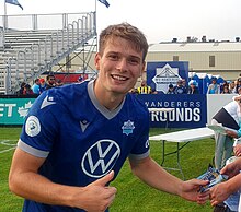 Man in a football jersey looking at the camera, smiling and giving the thumbs up sign