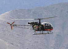Vrtulník v letu, na hornatém pozadí