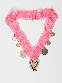 Pink protective neckband with a heart-shaped pendant and coins designed to distract the evil eye, 1944, Basel. In the Jewish Museum of Switzerland's collection. Judisches Halsgezeig.jpg