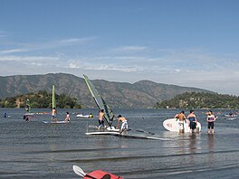 Windsurfing di danau, dengan bukit-bukit di luar