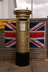 Gold post box and Union flag outside Lowdham Post Office, Nottinghamshire.