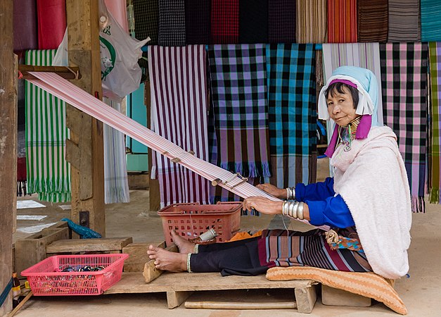 頸部配帶銅圈的巴东族妇女正在使用织布机。摄于缅甸大其力。