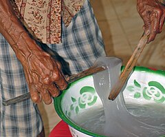 Using a special wooden fork called gata-gata to separate a serving from the bowl of 'papeda', a glue-like staple dish in West Seram, Maluku, Indonesia.