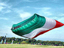 A kite in the shape of the flag of Kuwait. The size when flat is 42 by 25 meters (138 ft x 82 ft), 1,050 square meters (11,300 sq ft). While flying it becomes a little smaller (about 900 square meters (9,700 sq ft)) due to curvature of the edges when inflated. Worlds Largest Kite - Aloft - Taken in 2004.jpg