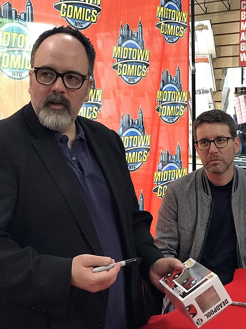 Comics writer Gerry Duggan and Deadpool film co-writer Rhett Reese autographing a Funko Pop figure of the character during a signing for Deadpool #300