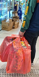 A man carrying bags of joss paper goods in a shopping mall Tai Po HK.jpg