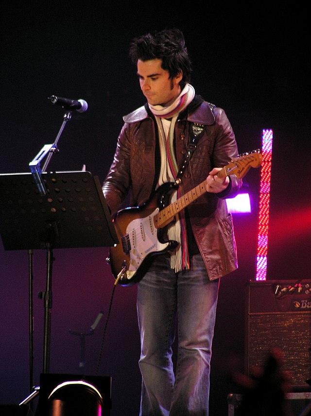 Kelly Jones playing guitar and looking at music notes on stage