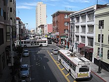 A 30 bus (lower right) headed north after emerging from the Stockton Street Tunnel in 2009. A 1 California trolleybus passes by on Sacramento Street. N on Stockton (3955731309).jpg