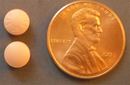 Quetiapine (Seroquel) 25 mg tablets, next to US one-cent coin for comparison