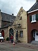 Bakstenen huis,met topgevel en poortmuur aan de straat