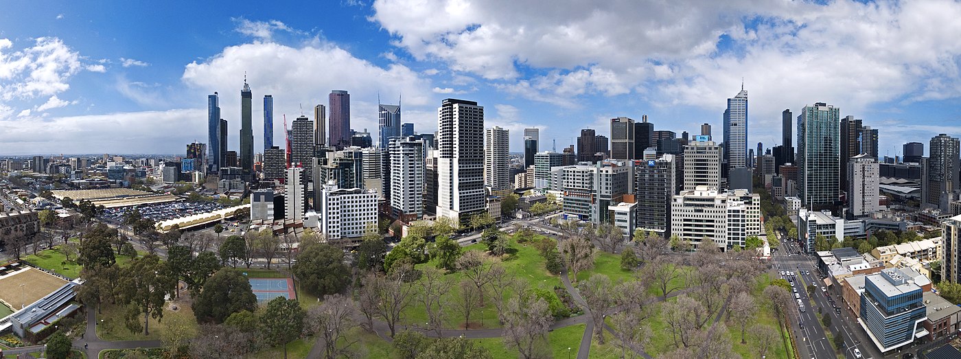 Panorama of city with park trees in foreground and many multi-storey buildings on the horizon