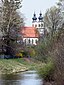 Durchblick die Prien entlang auf die Kirche Mariä Lichtmess in Aschau im Chiemgau, vom Steg an der Ludwig-Thoma-Straße aus.