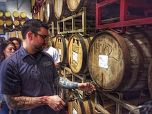 A beer sommelier tapping a barrel for a taste at Nebraska Brewing Company Beer sommelier at work.jpg