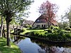 Boerderij onder hoog rieten schilddak met voorgevel met houten beschot onder het wolfschild en bedrijfsdeel met gedeeltelijk houten wanden