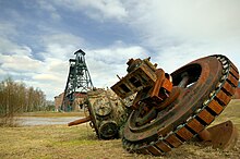 old equipment lies in the foreground while the two headframes of the mining elevator are in the background.
