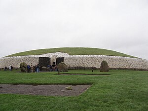 A large, circular stone tomb with a top covered with a thin grass.