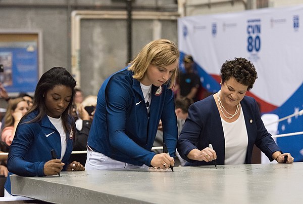 Ledecky (middle) and fellow Olympic champion Simone Biles (left) sign steel plate of USS Enterprise (2017)